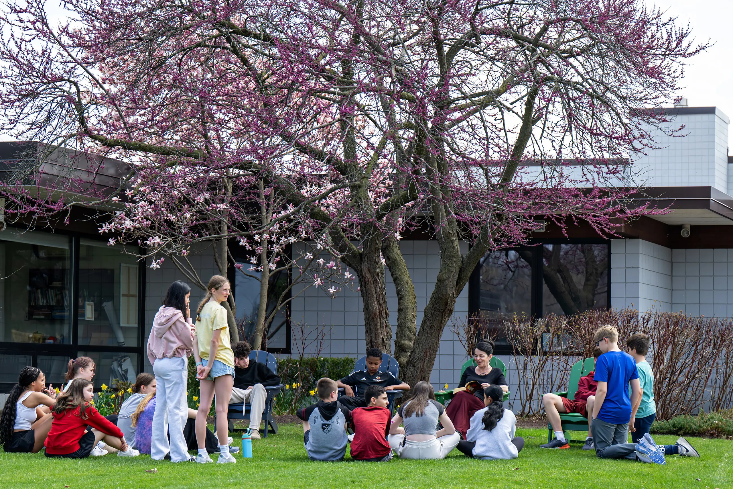 Students reading with teacher outside